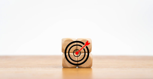 木桌背景上带有目标图标的木块。箭在靶心上。商业成功，投资目标，机会挑战，目标战略，成就焦点概念。图片下载
