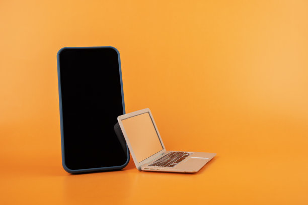 橙色背景的智能手机和笔记本电脑，数字商店，移动应用程序，送货和网上购物图片下载