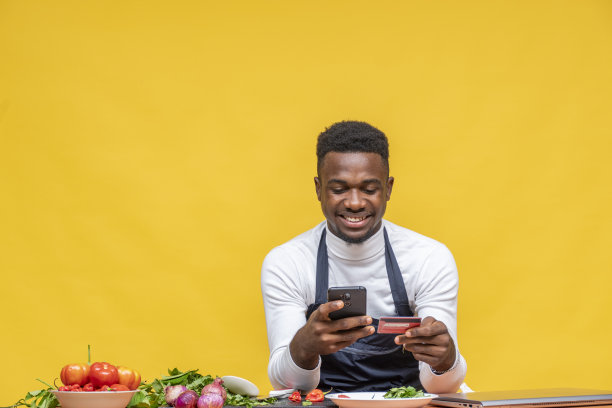 非洲男性厨师在准备食物时拿着手机和信用卡图片下载