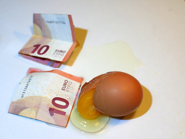 10欧元纸币靠近一个破鸡蛋，白色背景。图片下载