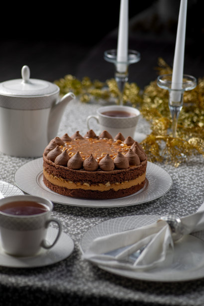 圣诞餐桌上有蛋糕。圣诞节和新年的家庭茶话会。餐桌上装饰着金箔和蜡烛图片下载