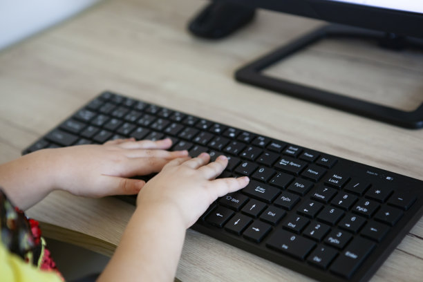 一个学前班的小女孩在图书馆用电脑键盘写字。图片下载