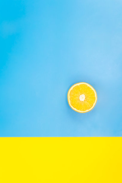 蓝色和黄色背景上的半个橙子，平面，极简主义。图片下载