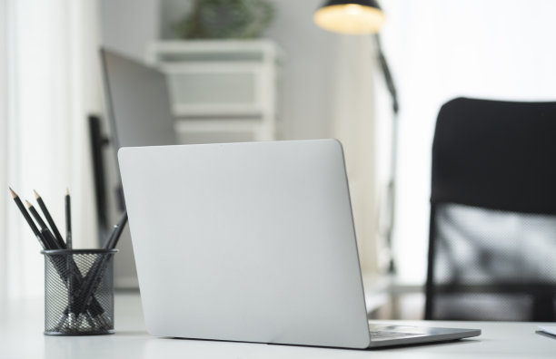 现代化的工作场所，笔记本电脑，笔筒和笔记本在白色的桌子上。图片下载