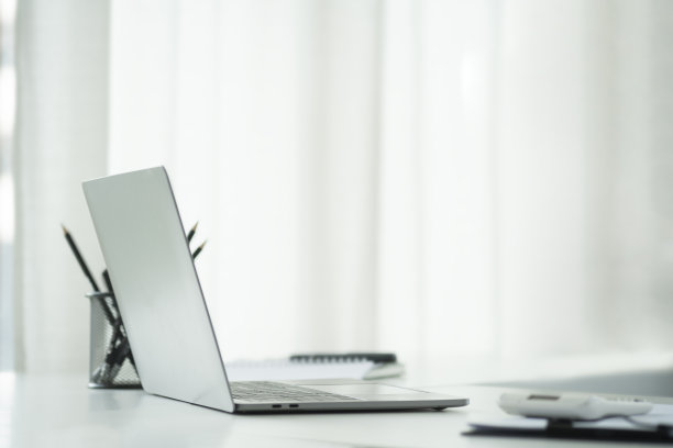 侧视图笔记本电脑，计算器，文件和笔记本电脑和白色办公桌。图片下载