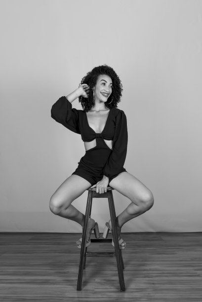 一个年轻女子坐在木凳上的黑白肖像。图片下载