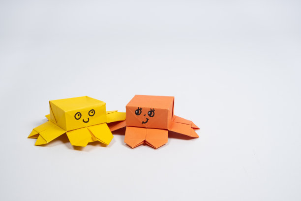 两只可爱的黄色和橙色折纸章鱼在白色背景，纸动物雕像图片下载