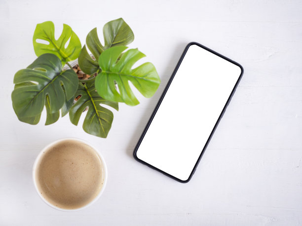 俯视图，智能手机与空白屏幕和热咖啡杯，种植在乡村木。平铺，留出文字空间。图片下载