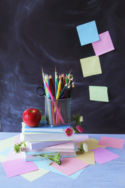一堆课本，多色铅笔，一个红苹果，背景是学校黑板和笔记纸，教育用品，教育图片下载