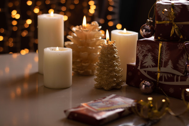 照片盒和礼物放在桌子上，背景是点燃的蜡烛，挂着节日花环图片下载