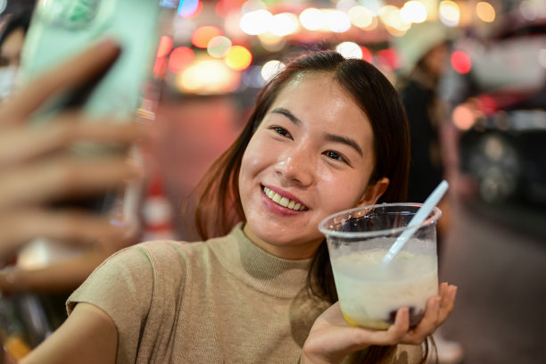 快乐的女人用手机在街头小吃市场与甜点自拍图片下载