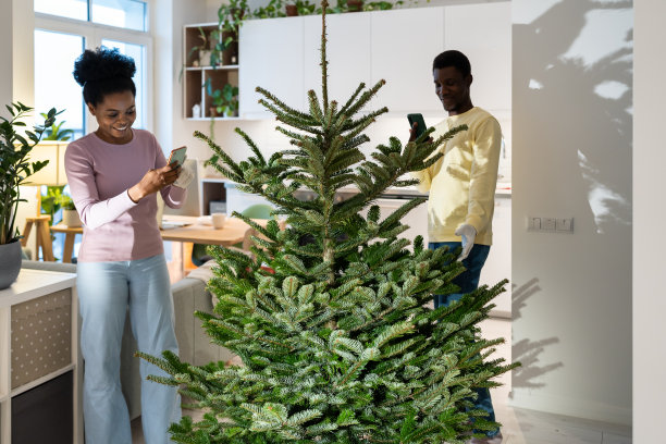 非洲裔妇女把新鲜的圣诞树照片与丈夫一起分享在社交媒体或博客上图片下载