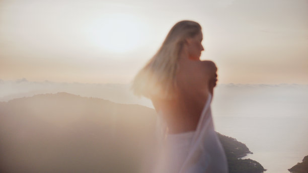 美丽的女神，金色的头发裹着白色的长袍在夕阳下。看风景图片下载