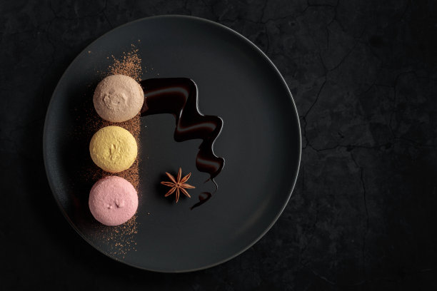 杏仁饼放在黑盘子里，配以巧克力酱和可可粉。图片下载