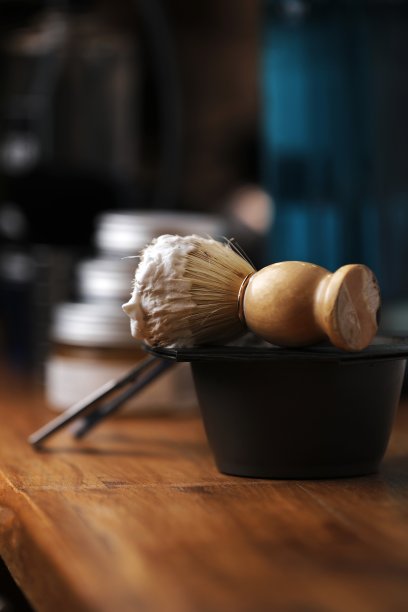 一套剃须设备和男士化妆品在木桌上，理发店。剃须概念与直剃刀，剃须刷和泡沫。男性胡须护理产品背景。图片下载