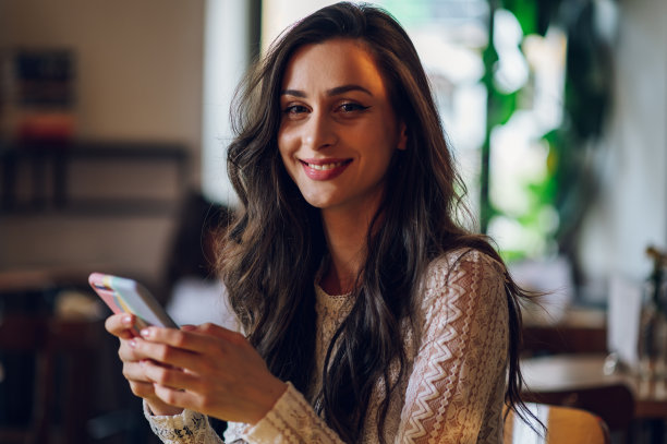 美丽的年轻女子在自助餐厅使用智能手机的肖像图片下载
