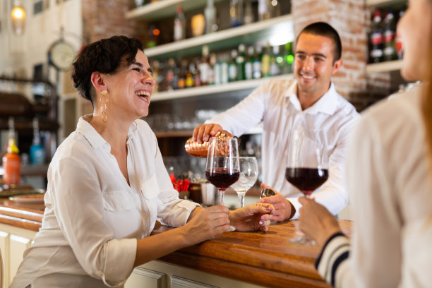 两个女朋友坐在餐厅的吧台边聊天边喝红酒图片下载