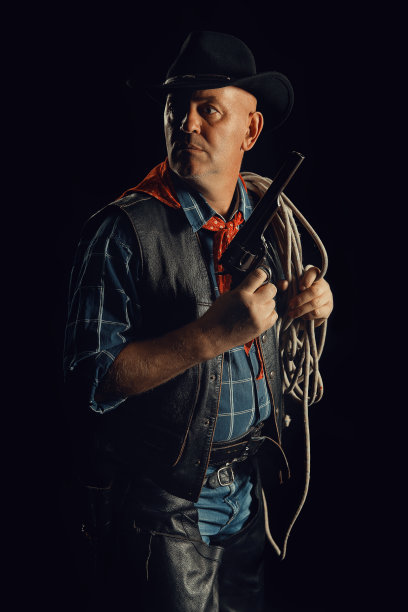 牛仔拿着左轮手枪，把套索挂在肩上图片下载