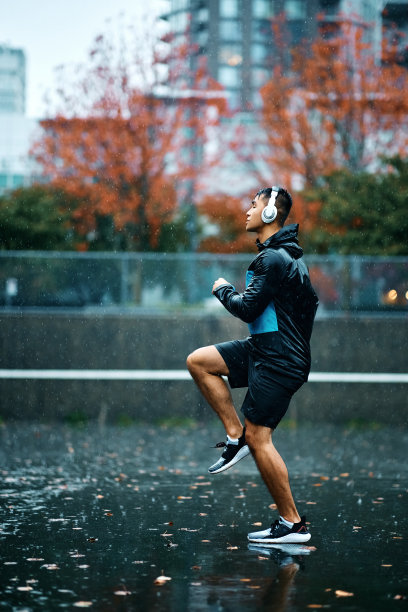 在户外雨中热身时，有动力的运动员在现场跑步。图片下载