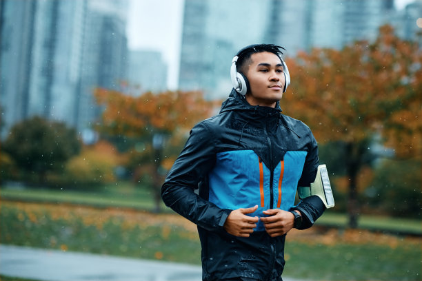 年轻的运动员在雨中跑步时戴着耳机听音乐图片下载