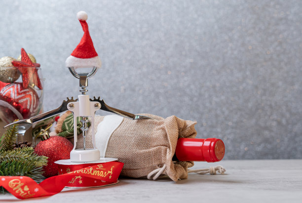 圣诞红酒和开瓶器与圣诞老人帽子装饰的桌子背景。图片下载