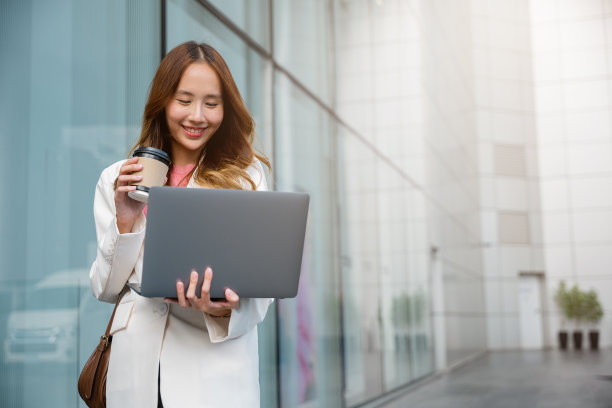 自信的女商人用笔记本电脑站着喝一杯咖啡图片下载