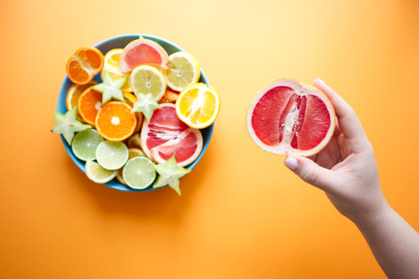 盛有切片柑橘类水果的大盘子，一只手拿着切片水果图片下载