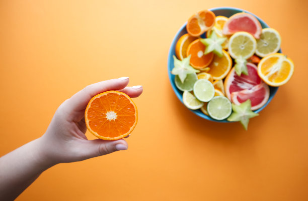 盛有切片柑橘类水果的大盘子，一只手拿着切片水果图片下载