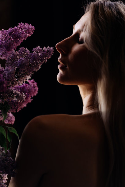 一个美丽的金发女人的侧面，一个裸露的肩膀和一束紫丁香图片下载
