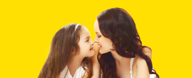 肖像拉近快乐的微笑母亲和年幼的女儿看着彼此孤立在黄色背景图片下载