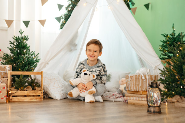 一个小男孩躺在为圣诞节装饰的儿童棚屋里图片下载