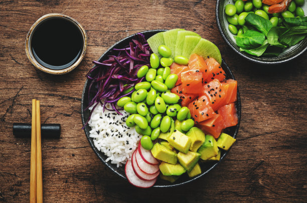 夏威夷烤肉碗，里面有三文鱼、牛油果、萝卜、毛豆、红卷心菜和白米饭。酱油，酸橙和芝麻酱。旧木桌背景，俯视图图片下载