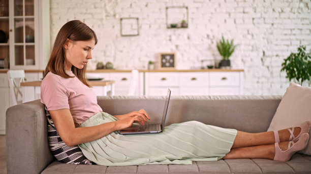 白人女商人躺在沙发上用笔记本电脑工作图片下载