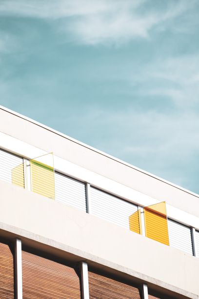 在一个阳光灿烂的日子里，一座建筑的正面在蓝色多云的天空下垂直拍摄图片下载