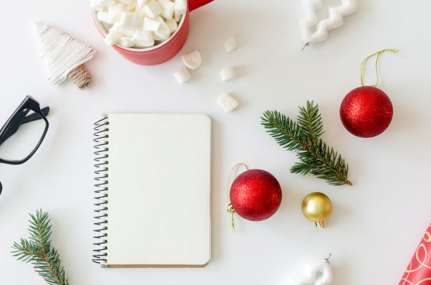 白色桌子上有空笔记本、眼镜、钢笔、巧克力和棉花糖，还有圣诞玩具。图片下载