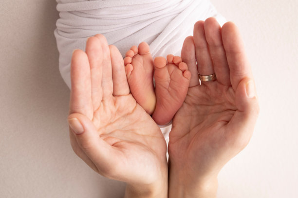 新生儿的腿，脚趾，脚和脚跟。用父母的手，爸爸，妈妈温柔地抱着孩子的腿。微距摄影，特写。黑白照片。高质量的照片。图片下载