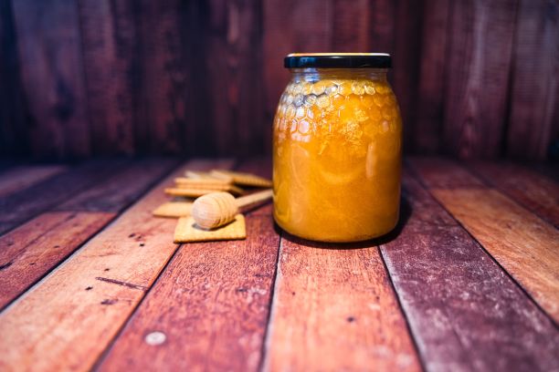 近距离的蜂蜜罐和饼干在一个木制表面图片下载