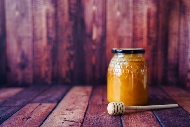一罐蜂蜜与蜂蜜勺在木制表面上模糊的背景图片下载