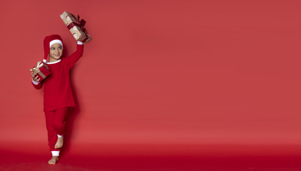 可爱的小男孩穿着圣诞睡衣，带着礼物。图片下载