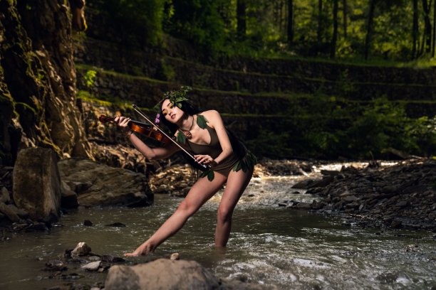 穿着棕色泳装的美女在公园的河里拉小提琴图片下载