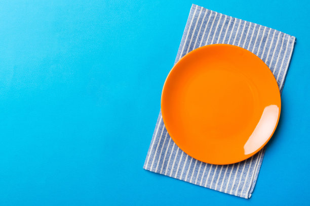 俯视图上的彩色背景空圆形红色盘子桌布上的食物。在餐巾纸上空出盘子，为你的设计留出空间图片下载