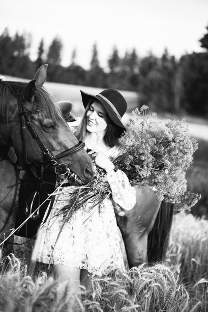 一个姑娘在田野里牵着一匹马。一个女人牵着马走。牵牛散步图片下载