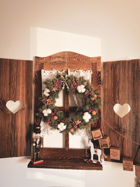 一圈云杉树枝映衬着木窗的背景。装饰用棉花，肉桂，胡椒，坚果。图片下载