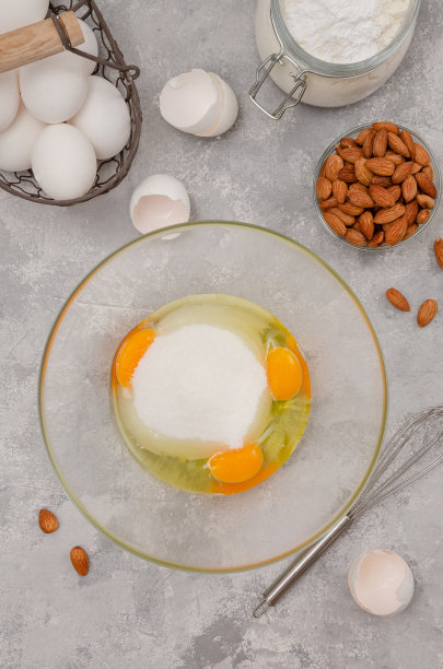 食谱一步一步来。制作意大利坎图尼饼干的过程。鸡蛋和糖放在碗里，背景是灰色混凝土。图片下载