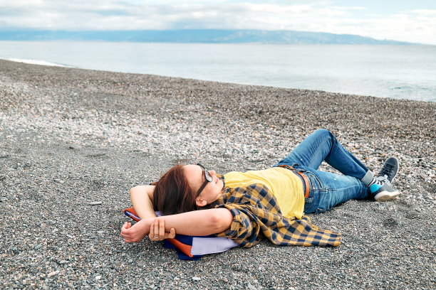 女人在温暖的格子衬衫休息，看海在冬天的海滩。旅行。幸福和谐理念。与自然统一。图片下载