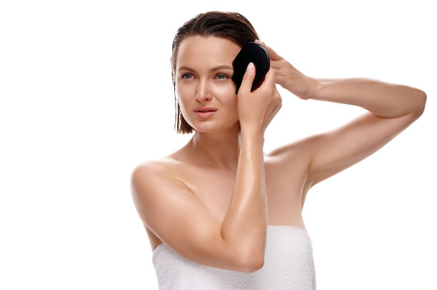 刮痧面部皮肤按摩。欧洲女子在白色浴巾按摩她的脸。隔离白色背景图片下载