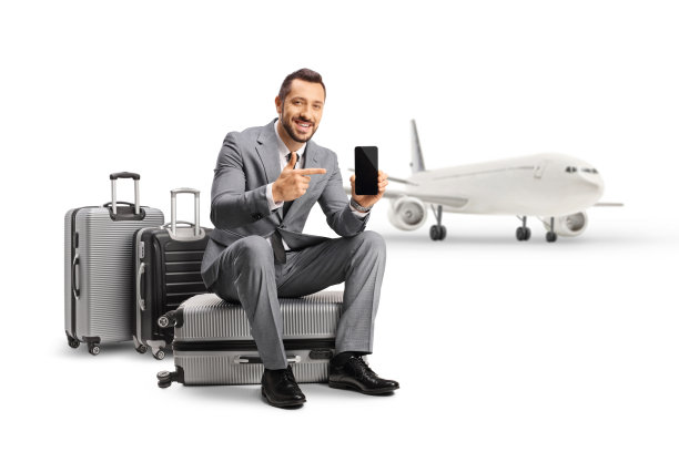 一名商人坐在飞机前的行李箱上，指着智能手机屏幕图片下载
