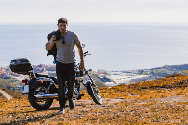 穿着皮夹克的摩托车手正从摩托车旁走开图片下载