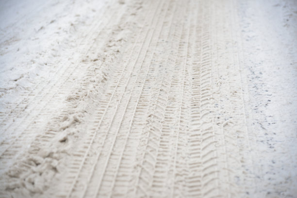 雪胎印。沥青被雪覆盖。危险的道路状况。冰冻地面上的汽车印。冰上有轮胎痕迹。图片下载