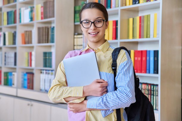十几岁的学生女孩在图书馆看着相机的肖像图片下载